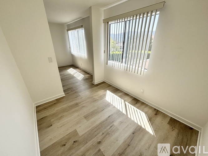 A room with wooden flooring and a window with blinds.