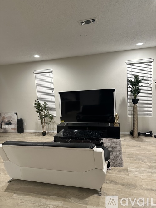 A modern living room with a white sofa and a black television.