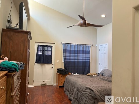 A bedroom with a bed, dresser, and ceiling fan.
