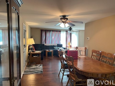 A living room with a wooden table and chairs, a couch, and a ceiling fan.