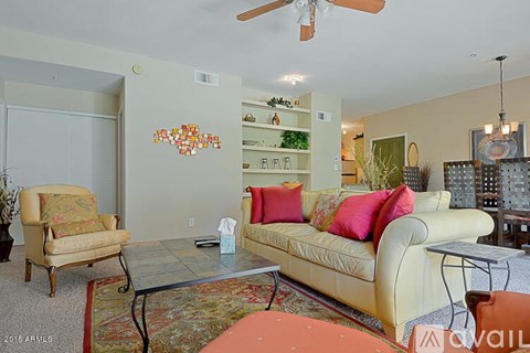 A living room with a yellow couch and a fan.