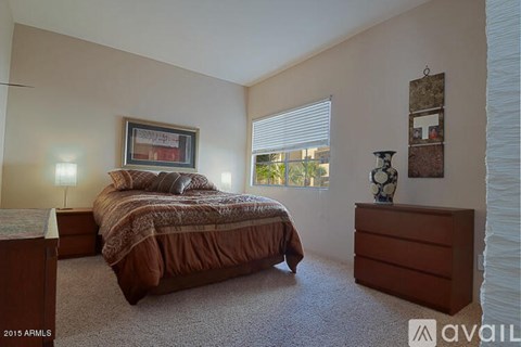 A bedroom with a bed, nightstand, and a window with blinds.