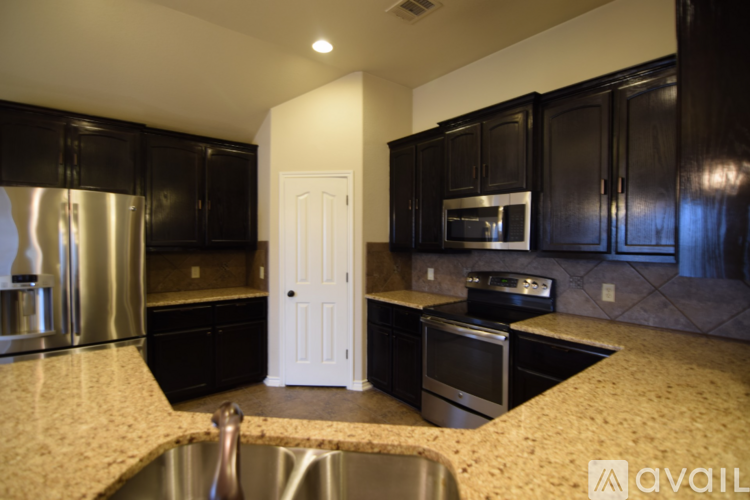 A kitchen with black cabinets and a white door.