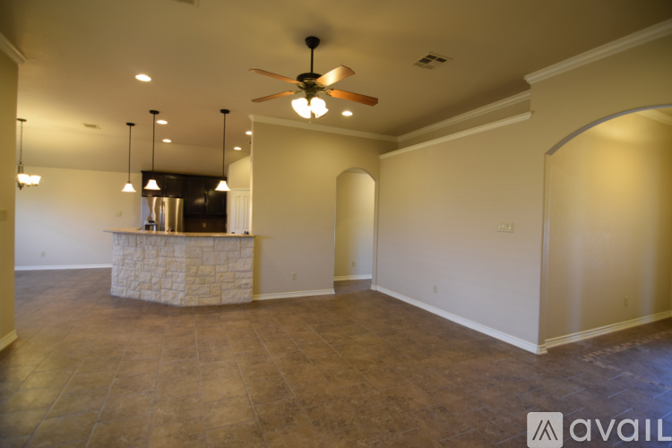 A spacious room with a stone fireplace and a ceiling fan.