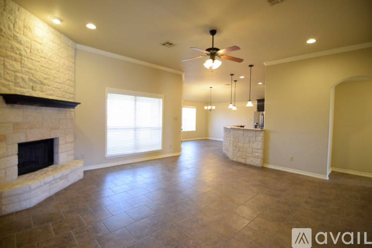 A spacious living room with a fireplace and a ceiling fan.