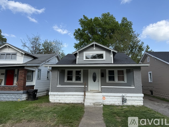 A house with a grey siding and a red door is for sale.