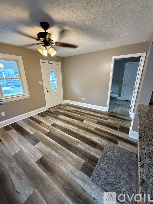 A room with a ceiling fan and wooden flooring.