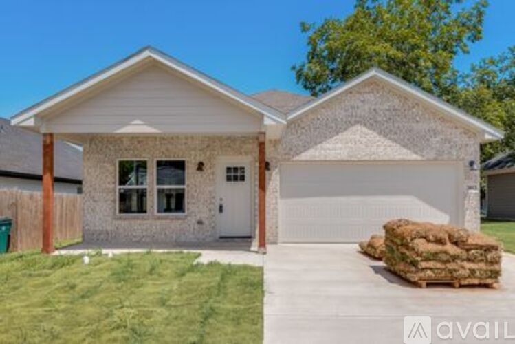 A house with a garage and a pile of hay in front of it.