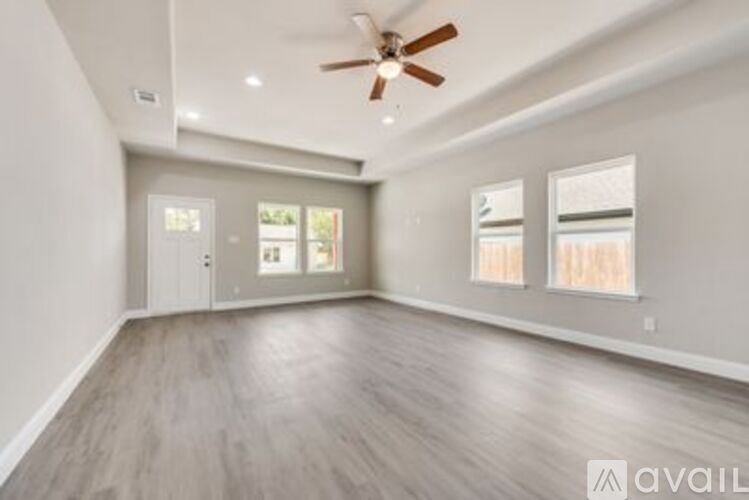 A spacious room with a ceiling fan and lighting, and a door leading to another room.