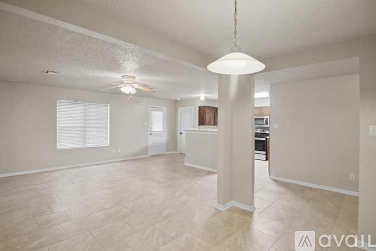 A spacious living room with a ceiling fan and light fixture.