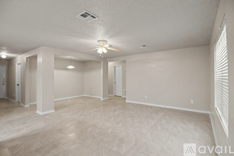 A spacious room with a ceiling fan and lighting fixture.