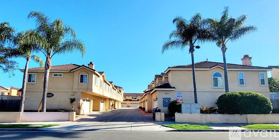 A row of houses with palm trees in front.