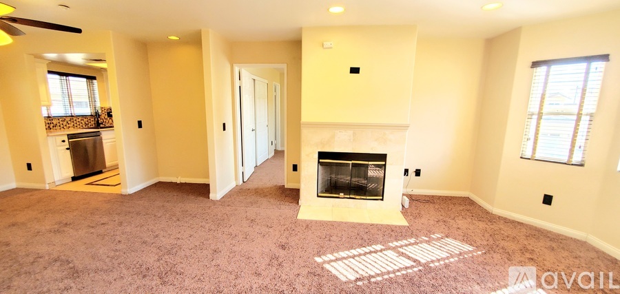 A spacious living room with a fireplace and a carpeted floor.