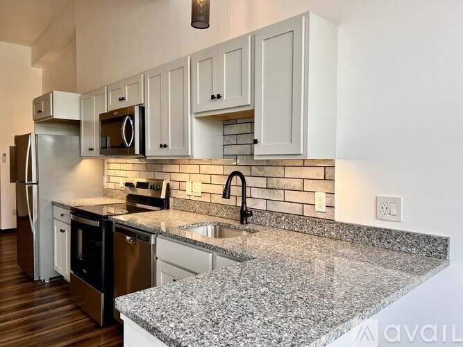 A kitchen with granite countertops and white cabinets.