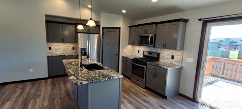 A kitchen with a granite counter top and wooden floors.