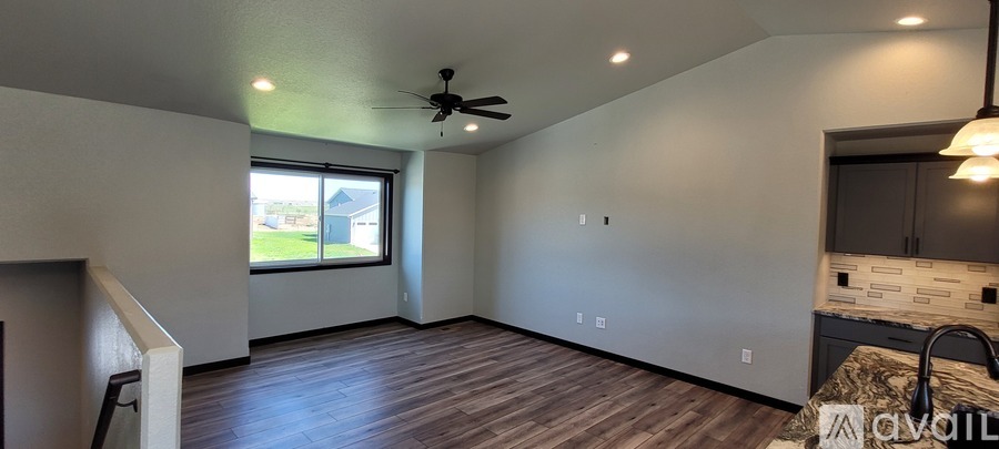 A room with a ceiling fan and a window overlooking a green yard.