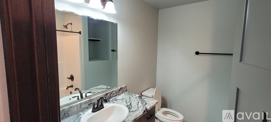 A bathroom with a sink, toilet, and mirror.