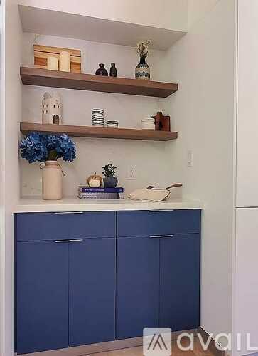 A kitchen with blue cabinets and shelves with decorative items.