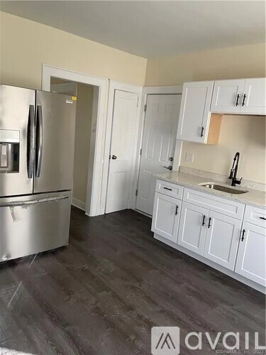 A kitchen with white cabinets and a stainless steel refrigerator.