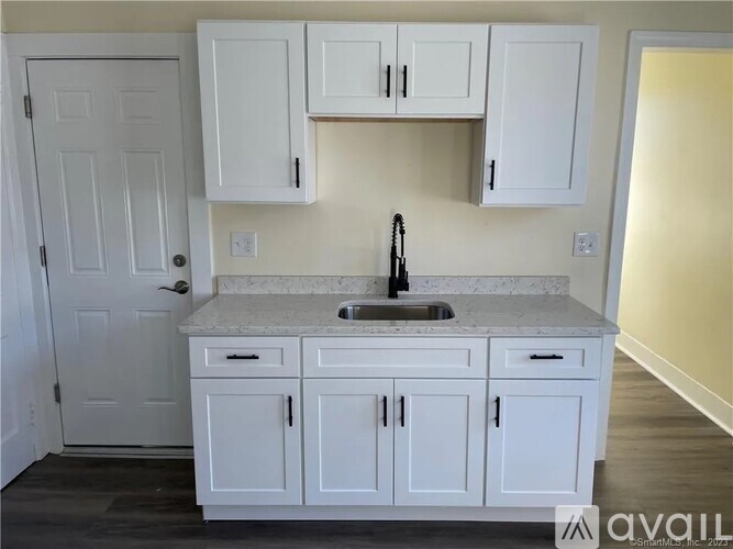 A kitchen with white cabinets and a marble countertop.