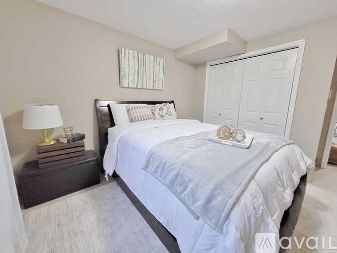 A bedroom with a large bed and a lamp on a side table.