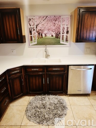 A kitchen with brown cabinets and a framed picture of a cherry blossom tree on the wall.