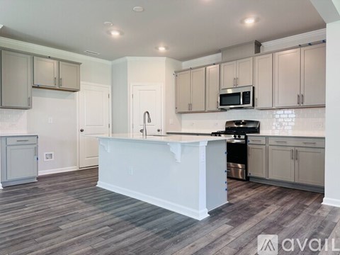 A kitchen with a white island and wooden floors.