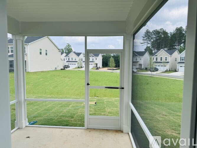 A view from a house looking out to a grassy area and other houses.
