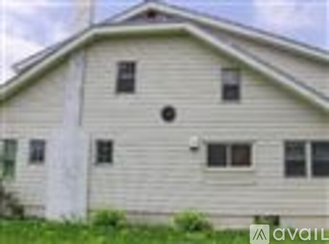A white house with a grey roof and a small window on the front.