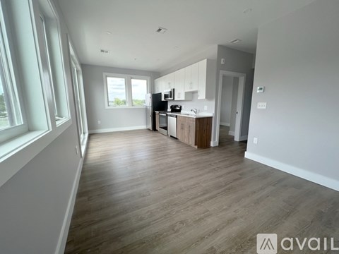 A spacious kitchen with wooden flooring and white walls.