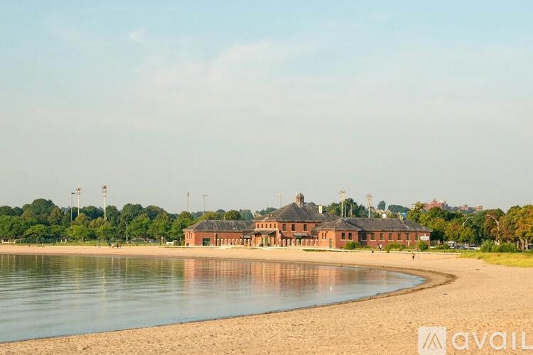 A beach with a building in the background and a body of water in the foreground.