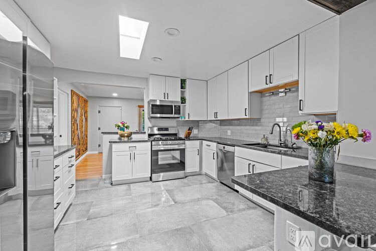 A kitchen with white cabinets and a black countertop.