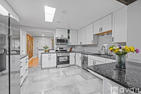 A kitchen with white cabinets and a black countertop.