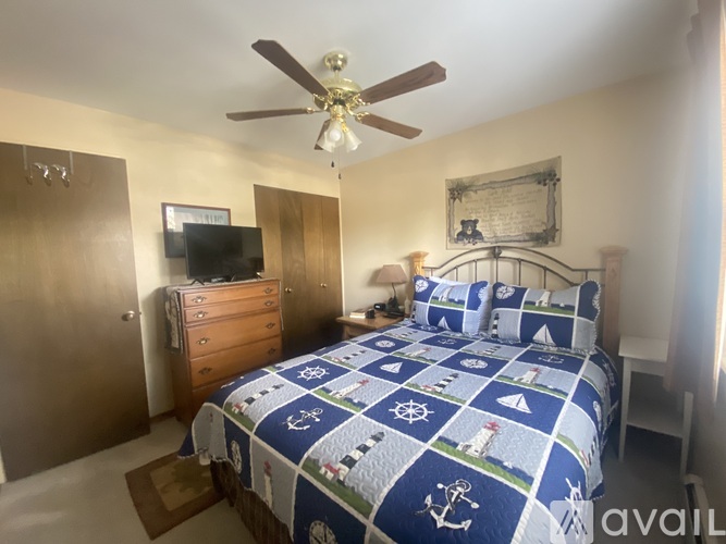 A bedroom with a bed, dresser, and ceiling fan.