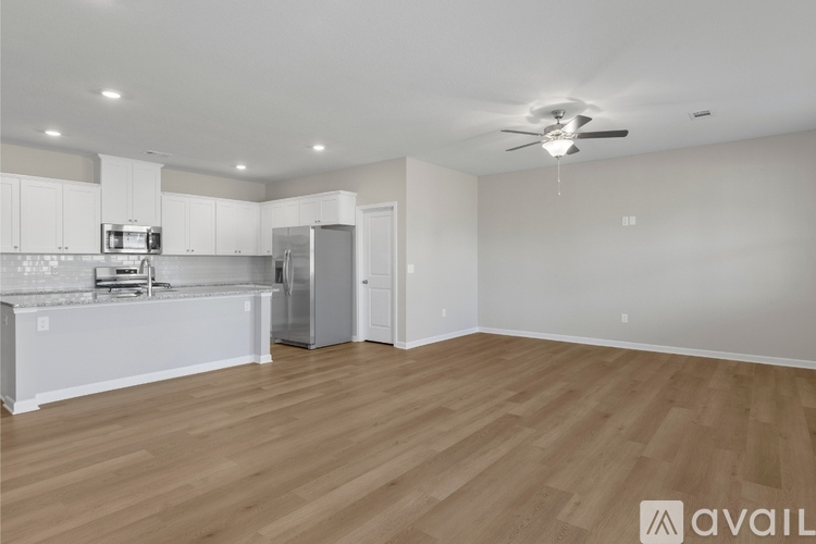 A spacious kitchen with white cabinets and a wooden floor.
