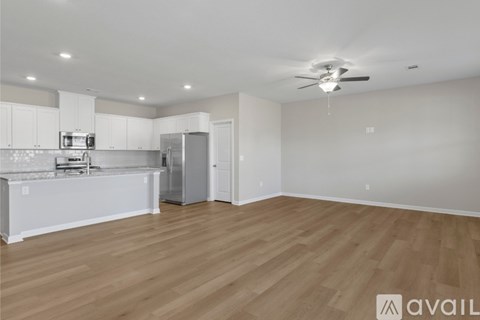 A spacious kitchen with white cabinets and a wooden floor.