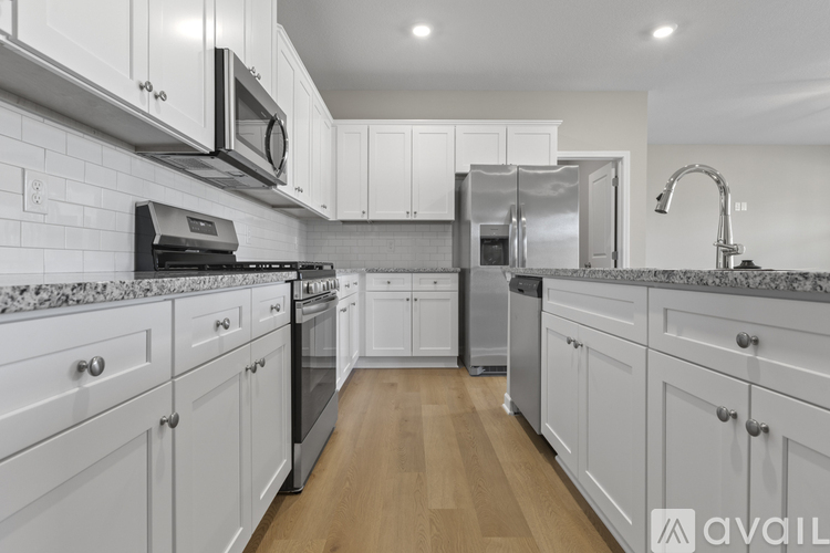 A kitchen with white cabinets and a wooden floor.