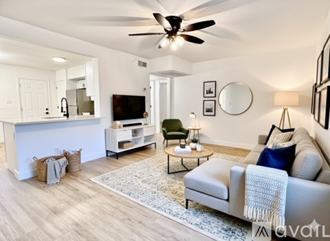 A living room with a grey couch and a white ceiling fan.