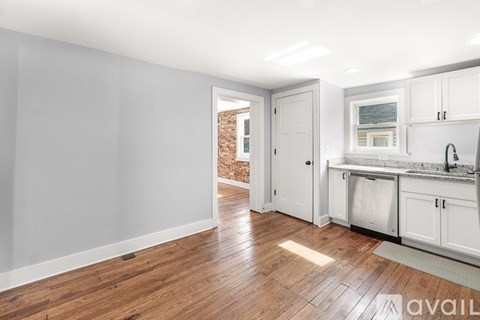 A kitchen with white cabinets and a wooden floor.