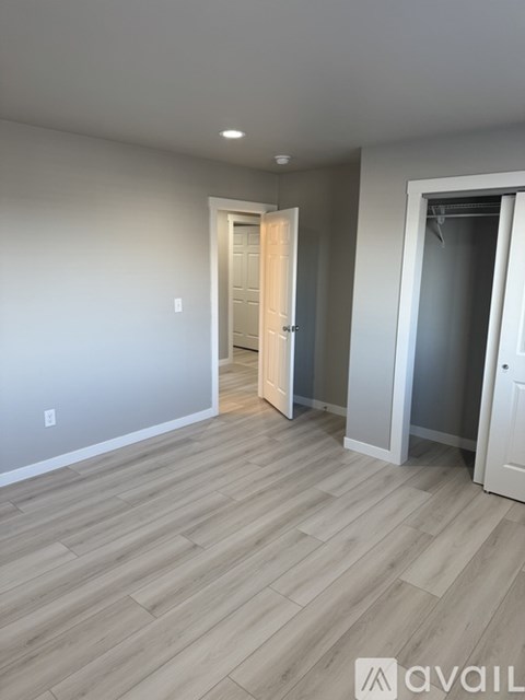 A room with wooden flooring and two doors, one of which is open.
