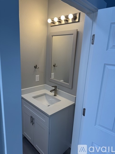 A bathroom with a sink and a mirror with lights above it.