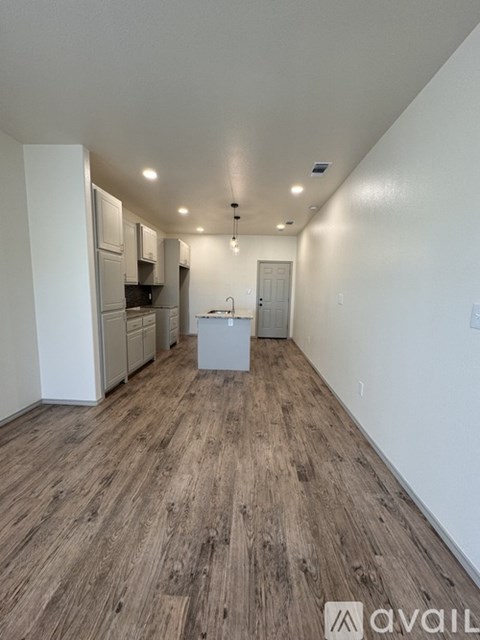 A kitchen area with wooden flooring and white walls.