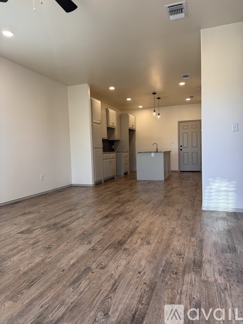 A spacious room with wooden flooring and a ceiling fan.