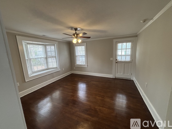 A room with a ceiling fan and wood flooring.