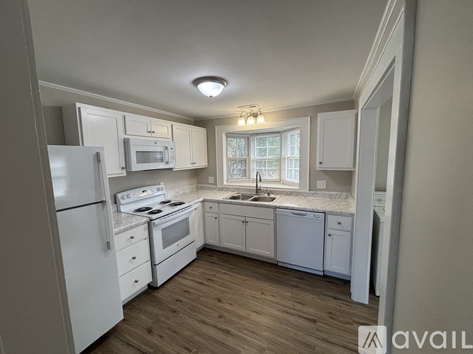 A kitchen with white appliances and wooden floors.