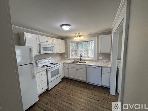 A kitchen with white appliances and wooden floors.