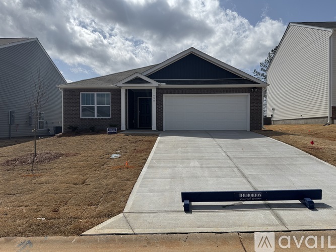 A house with a driveway and a bench in front of it.