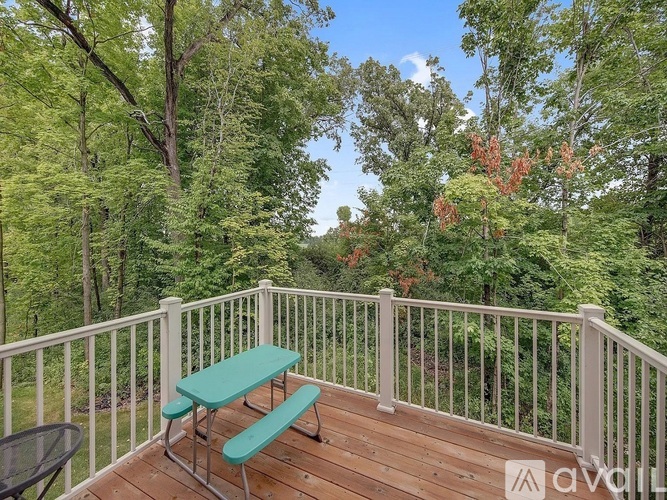 A wooden deck with a green bench and a white railing.
