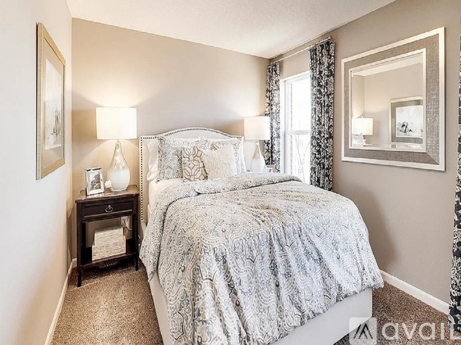 A bedroom with a large bed and a nightstand with a lamp.