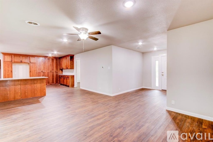 A spacious room with wooden floors and a ceiling fan.